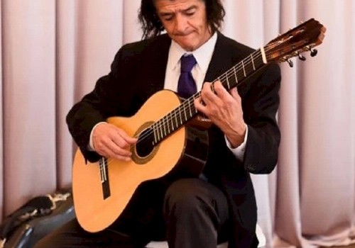 Classical Guitarist Patricio Contreras Playing his Guitar in front of a Pink Curtain