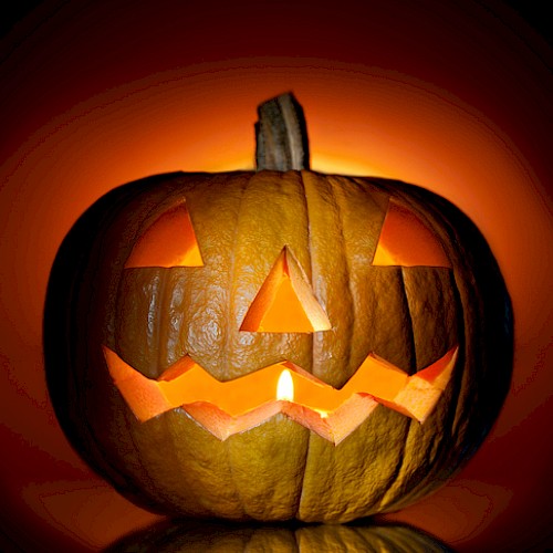 This image shows a carved jack-o'-lantern with a lit candle inside, creating an eerie glow against a dark background always ending the sentence.