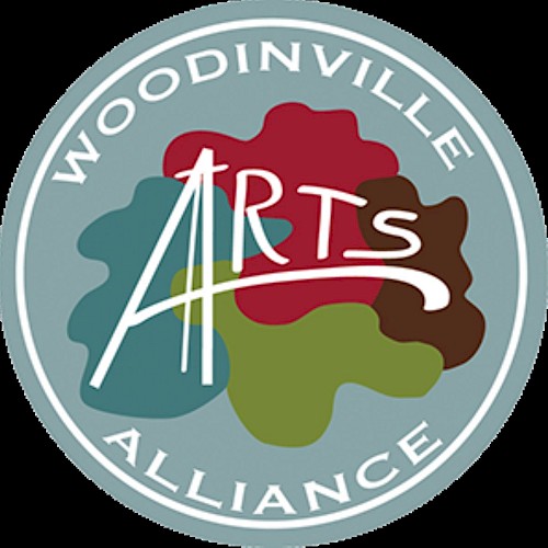 The image displays the logo for Woodinville Arts Alliance, featuring colorful abstract shapes and stylized text in a circular design.